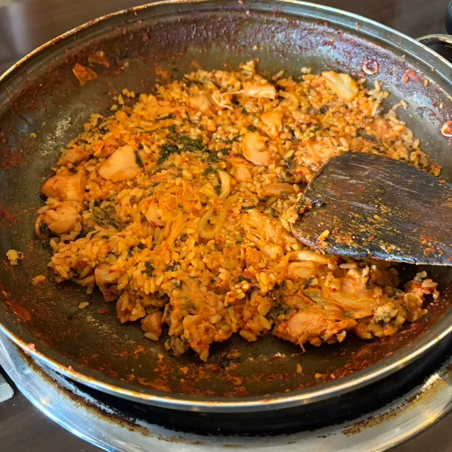 A bite of potato pancake topped with cheesy dakgalbi