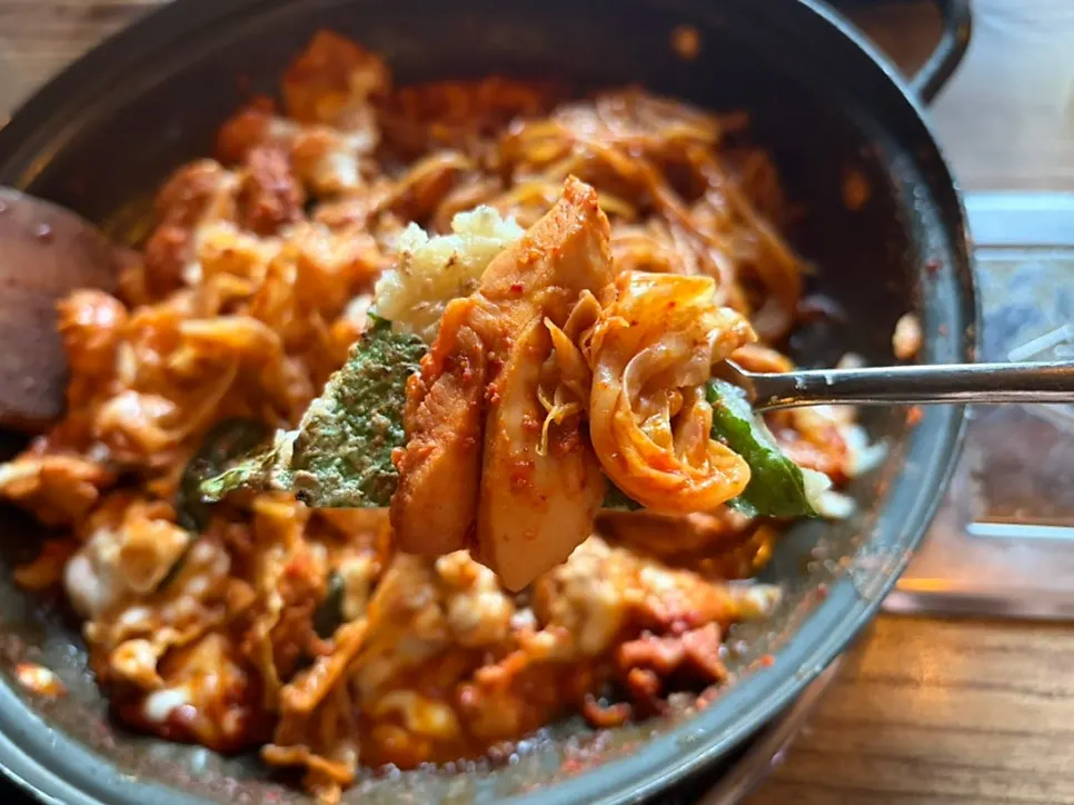 A bite of cheese dakgalbi piled onto potato pancake