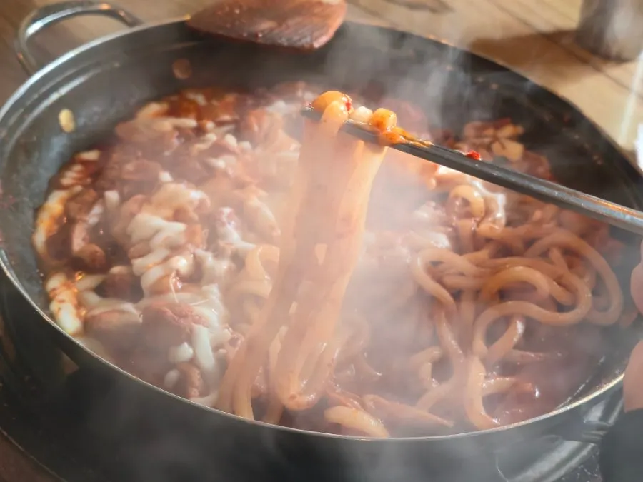 A bite of dakgalbi coated in cheese