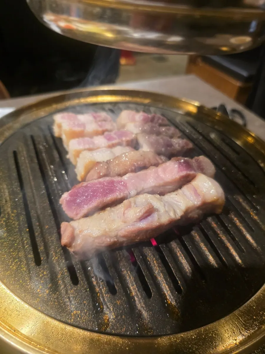 Thick pork belly grilling over charcoal