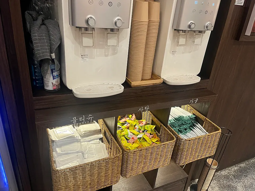 Self-service corner with water, paper cups, wet wipes, candy, and mouthwash