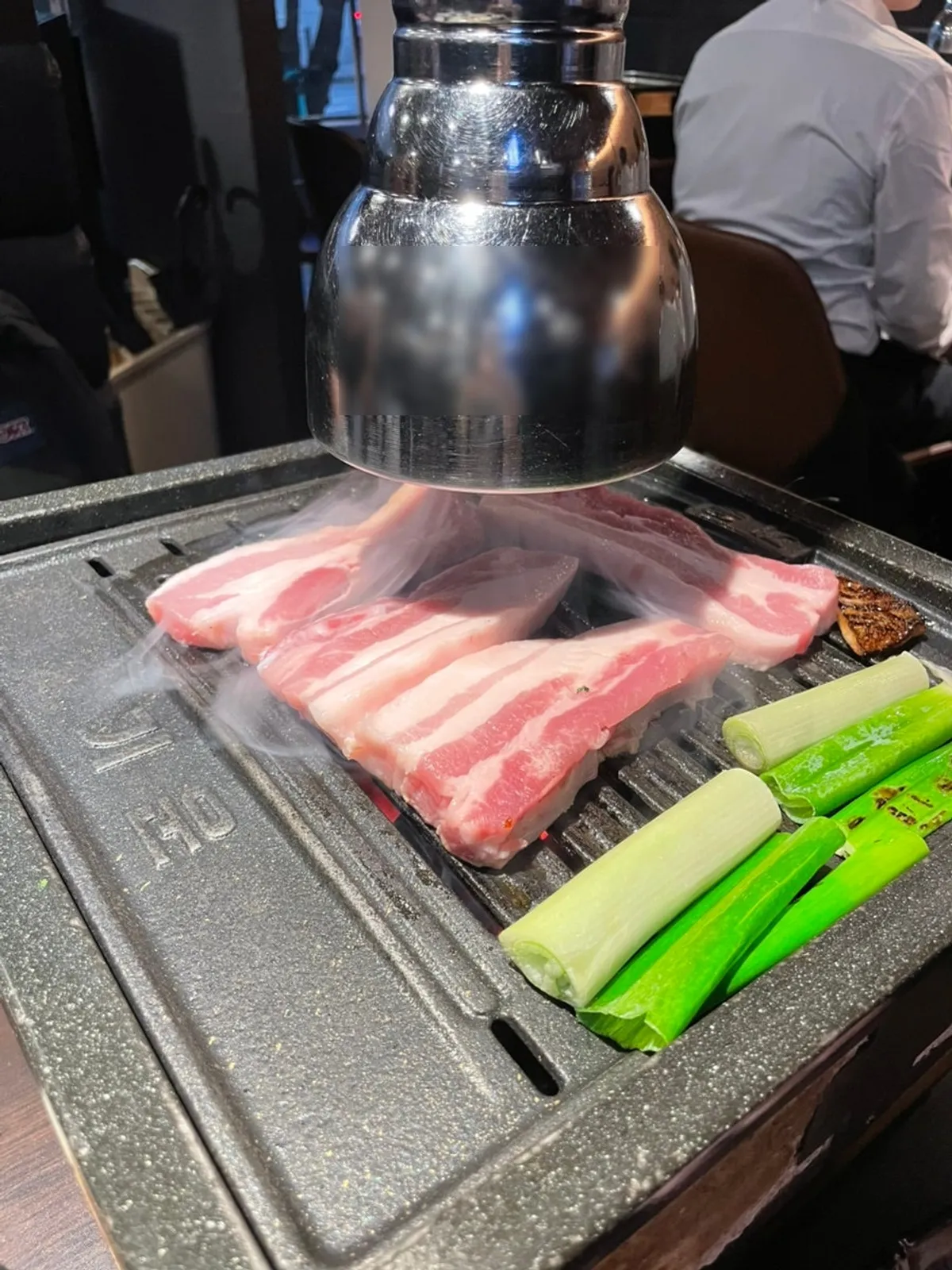 숯불 불판에서 구워지는 갈비삼겹과 파