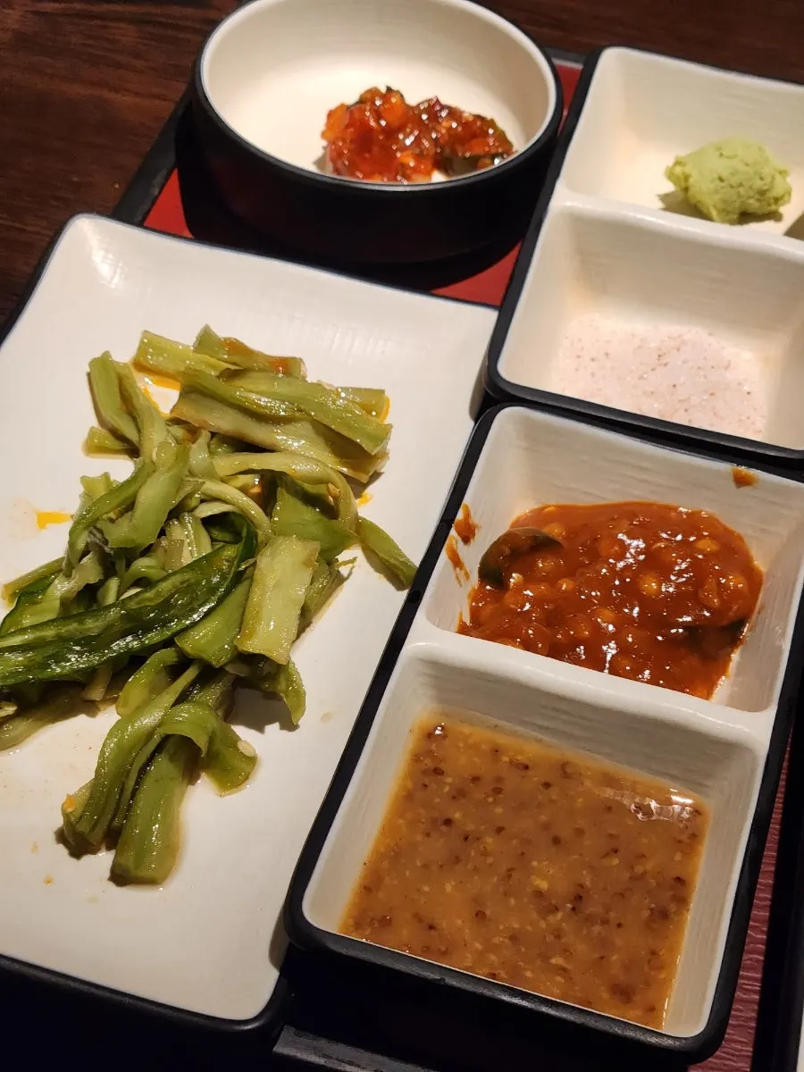Side dish spread with pickles, wasabi, and shredded green onion