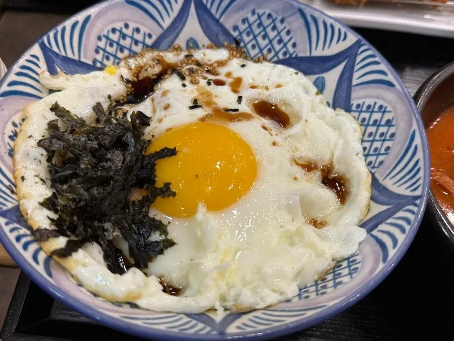 Bowl of rice topped with fried egg and seaweed flakes