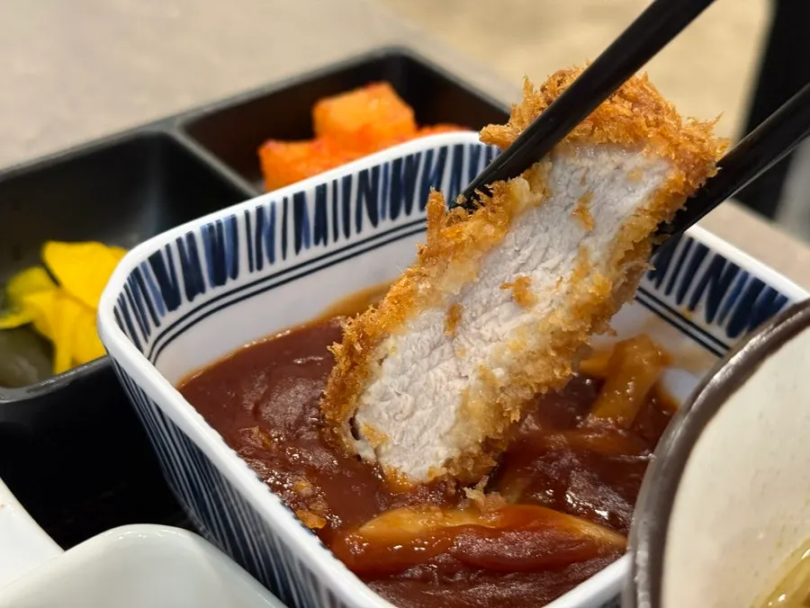 A crispy piece of pork cutlet dipped in sauce