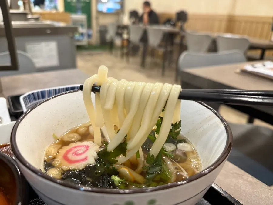 Bowl of mini udon with fish cake and crown daisy