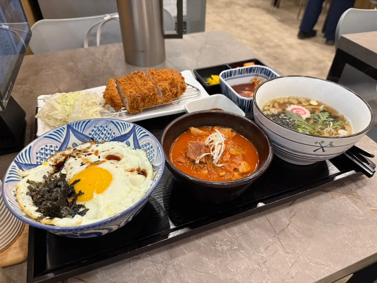 Full solo dining spread of egg rice, kimchi jjigae, pork cutlet and mini udon