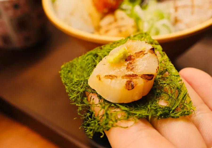 A piece of sashimi with wasabi placed on gim-tae seaweed