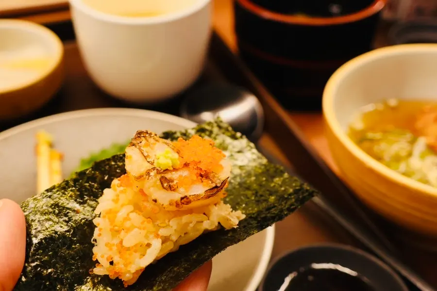 A piece of sashimi and a spoonful of rice held together