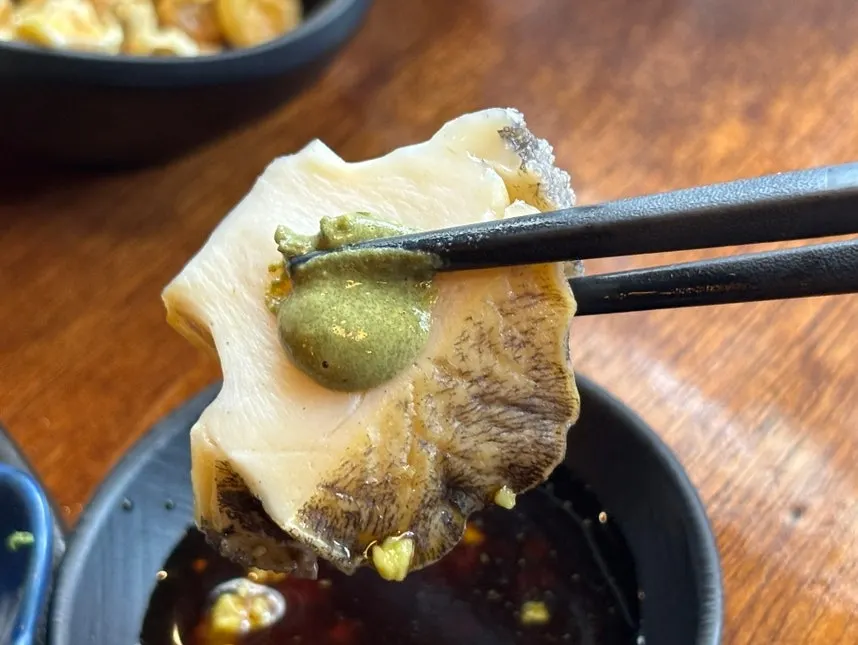 A piece of aged sashimi topped with wasabi and soy sauce