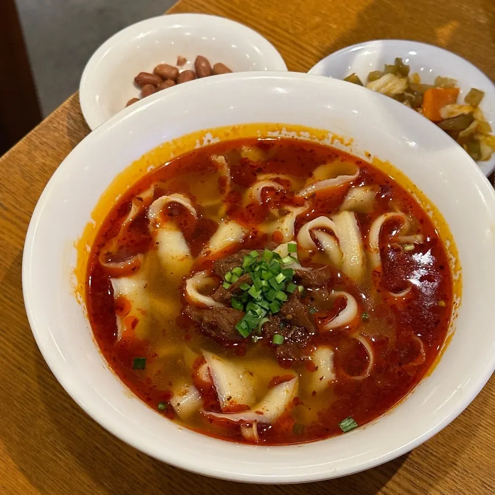 젓가락으로 들어 올린 넓적한 우육도삭면 면발