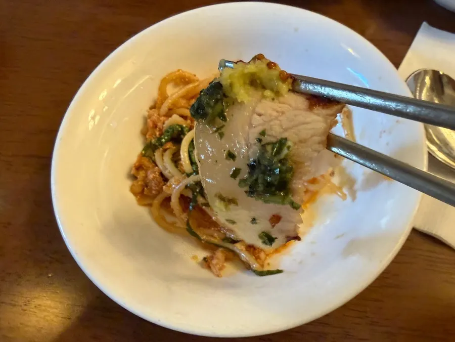 A single bite of well-grilled pork jowl