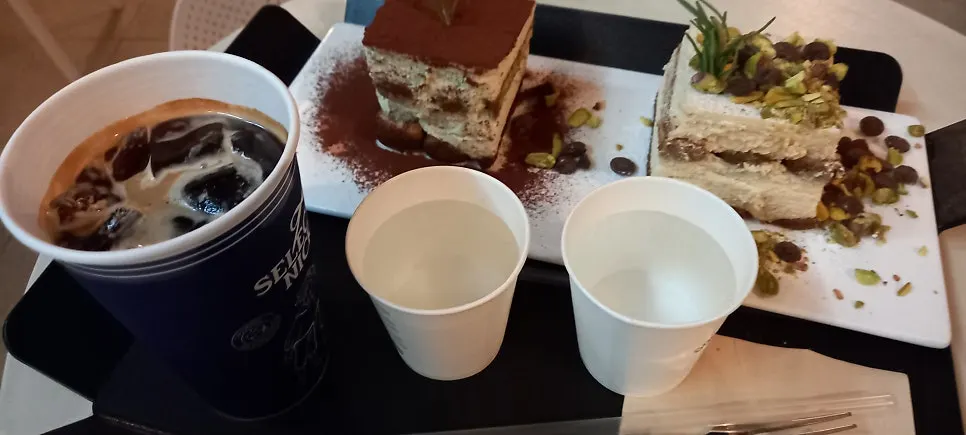 Table with two slices of tiramisu and an americano