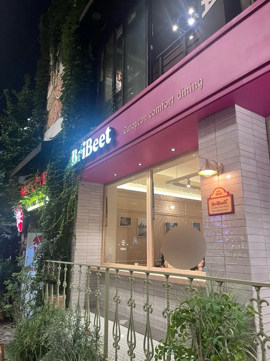 식물 장식과 메뉴 포스터가 있는 매장 외관