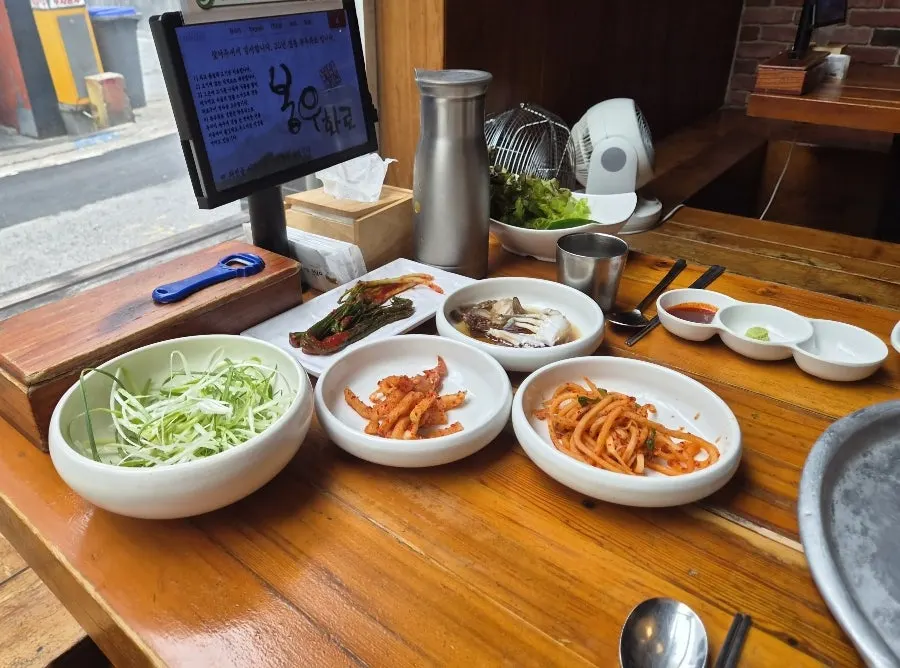 Table spread of scallion salad, seasoned radish and other Bongu Hwarro banchan