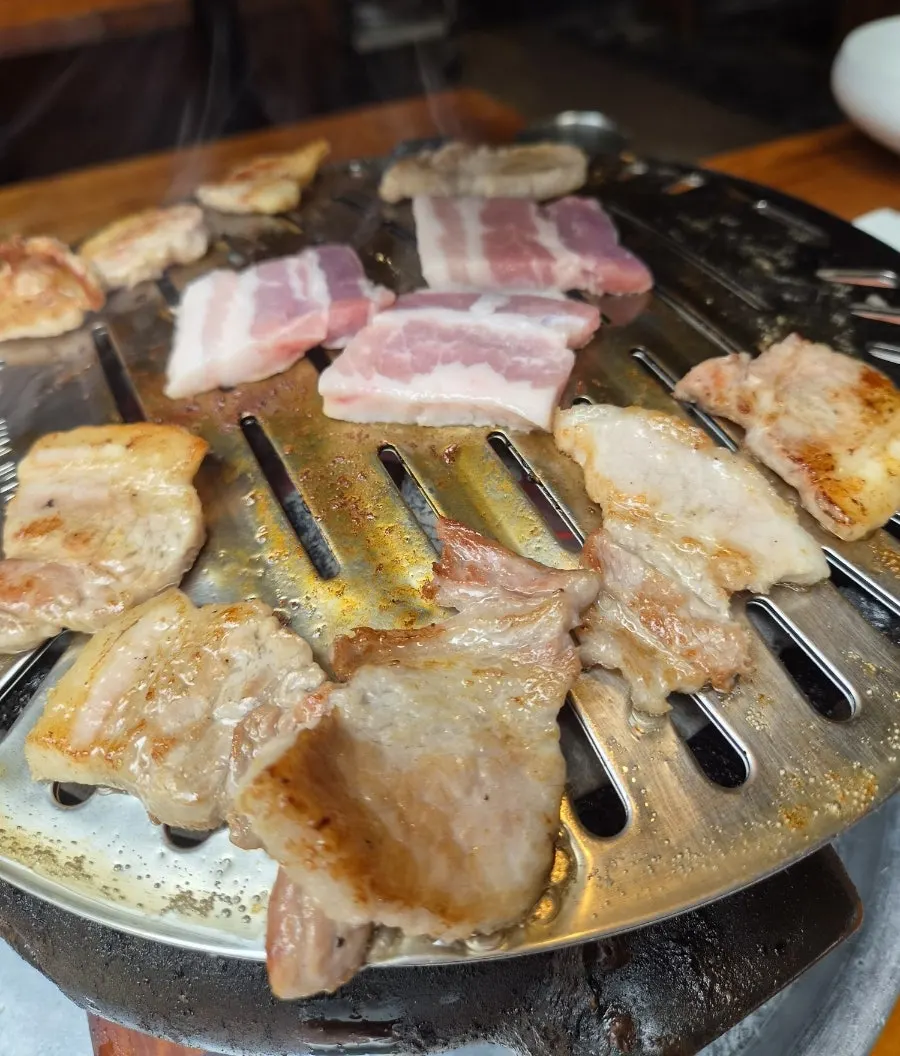 Flipping the grilling pork belly with tongs