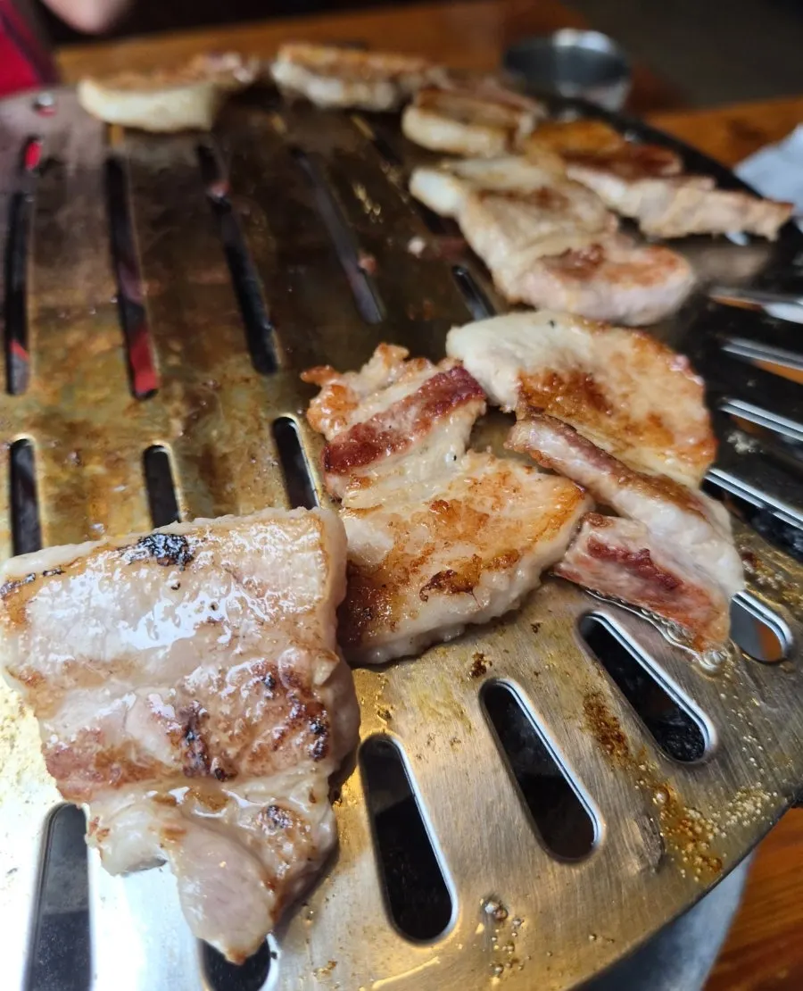 A piece of pork belly dipped in salt with wasabi on top