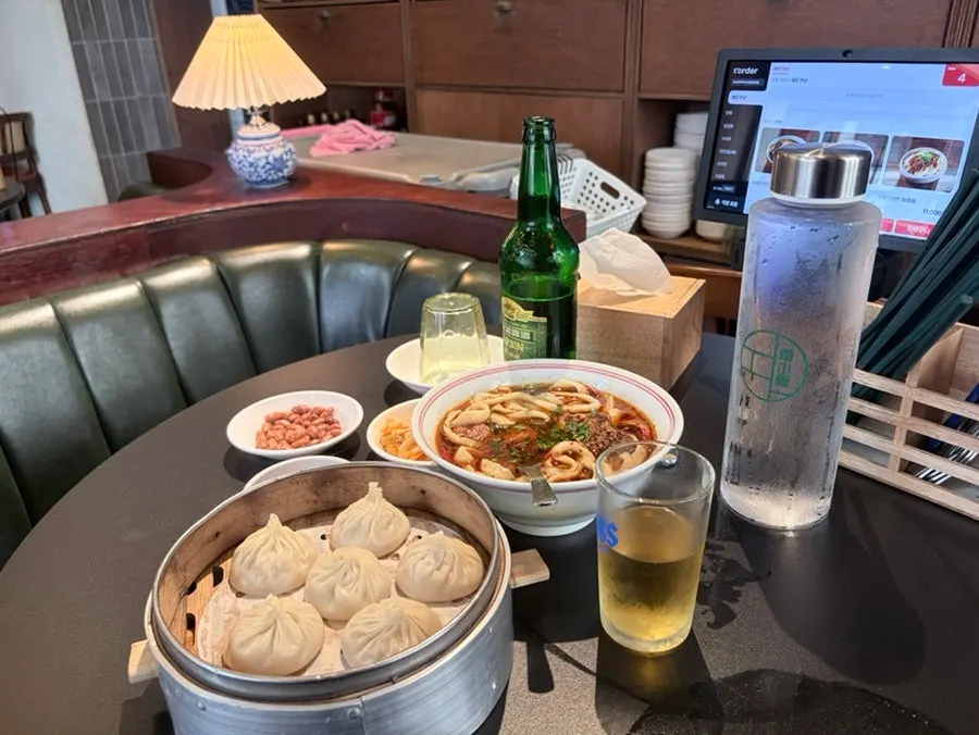Fideos de res estilo Sichuan, xiaolongbao y cerveza Harbin en la mesa