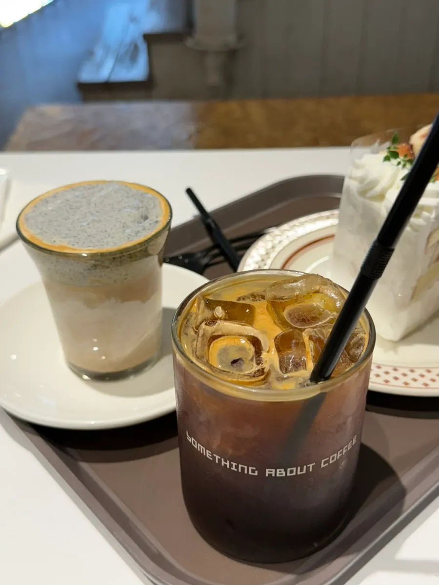 Black sesame cream latte, iced Americano, and fig fresh cream cake laid out together