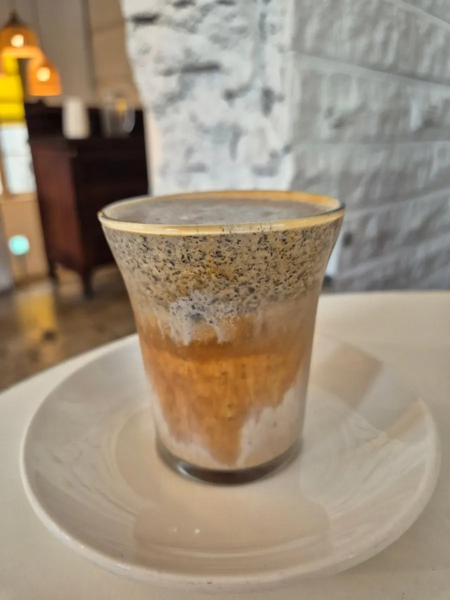 A cup of black sesame cream latte topped with cream