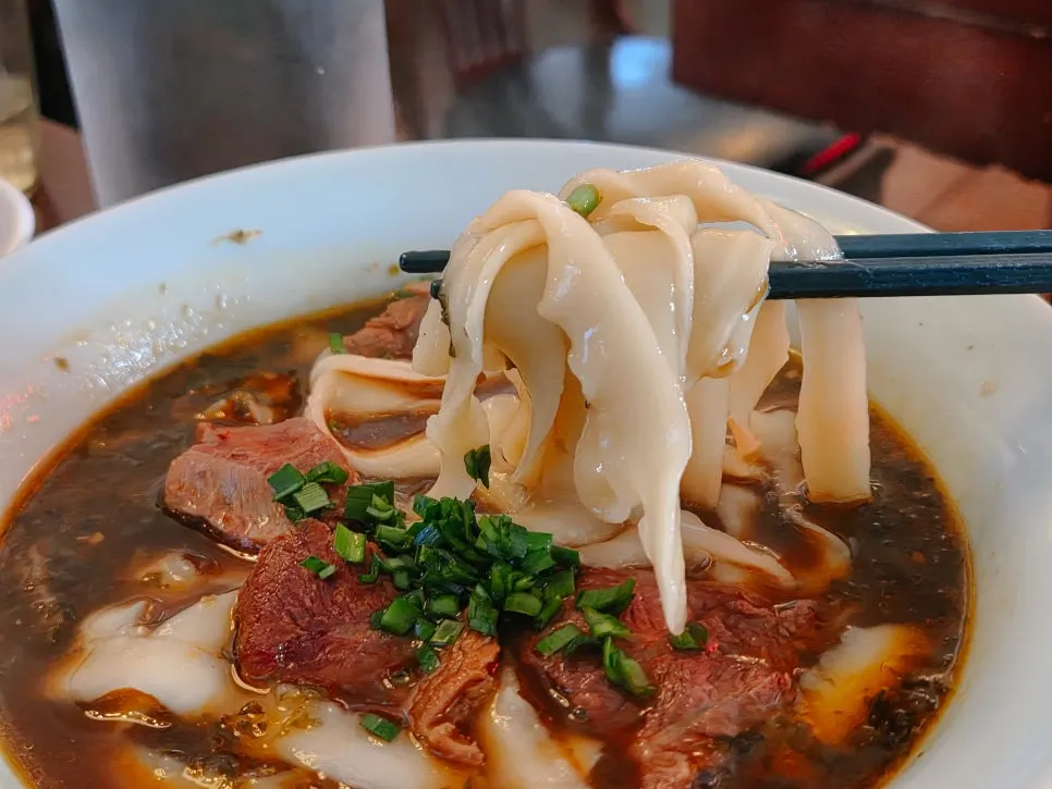 A bowl of Taiwanese-style beef hand-cut noodles topped with aronsatae
