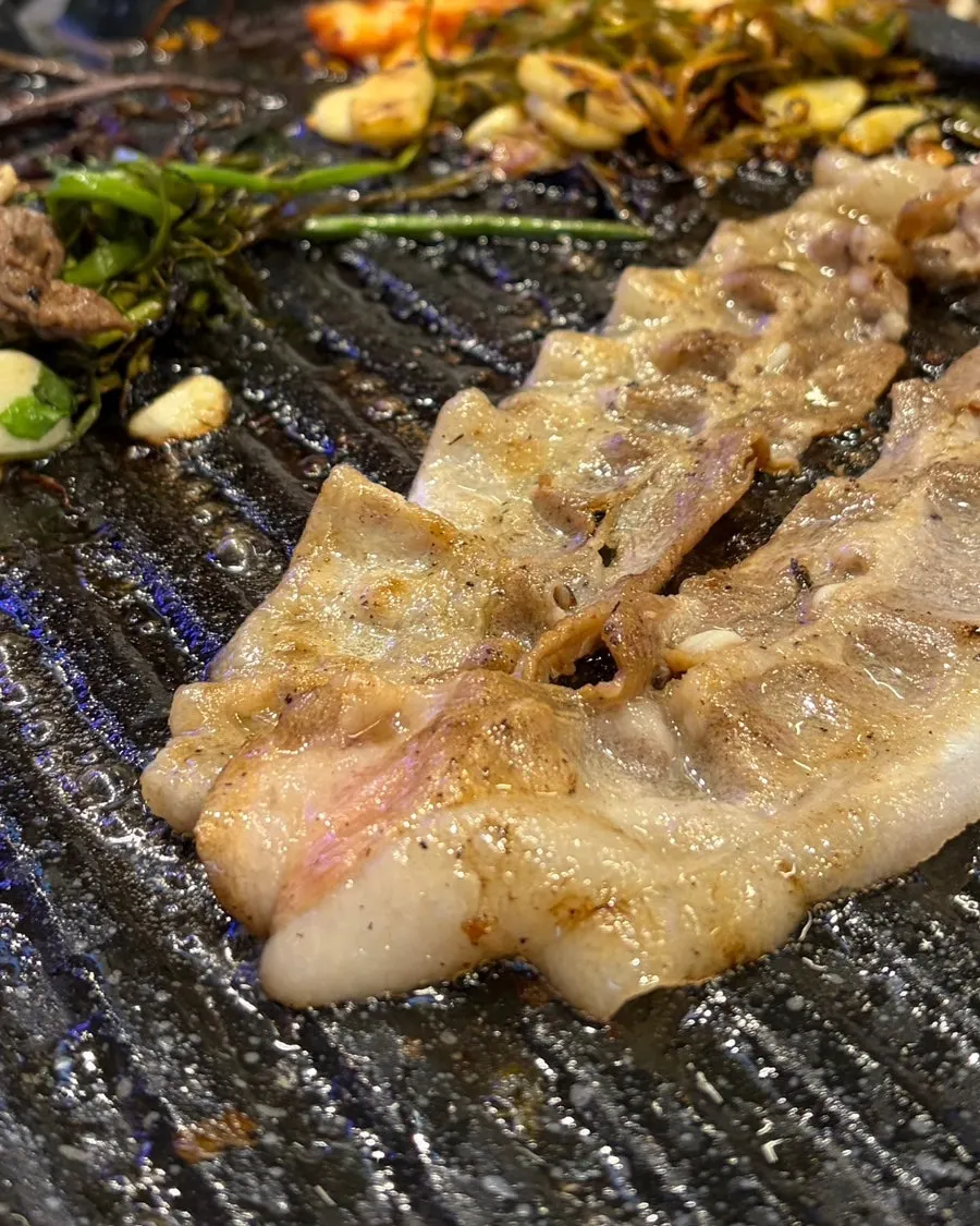 Thin-sliced meat on the grill at an outdoor table