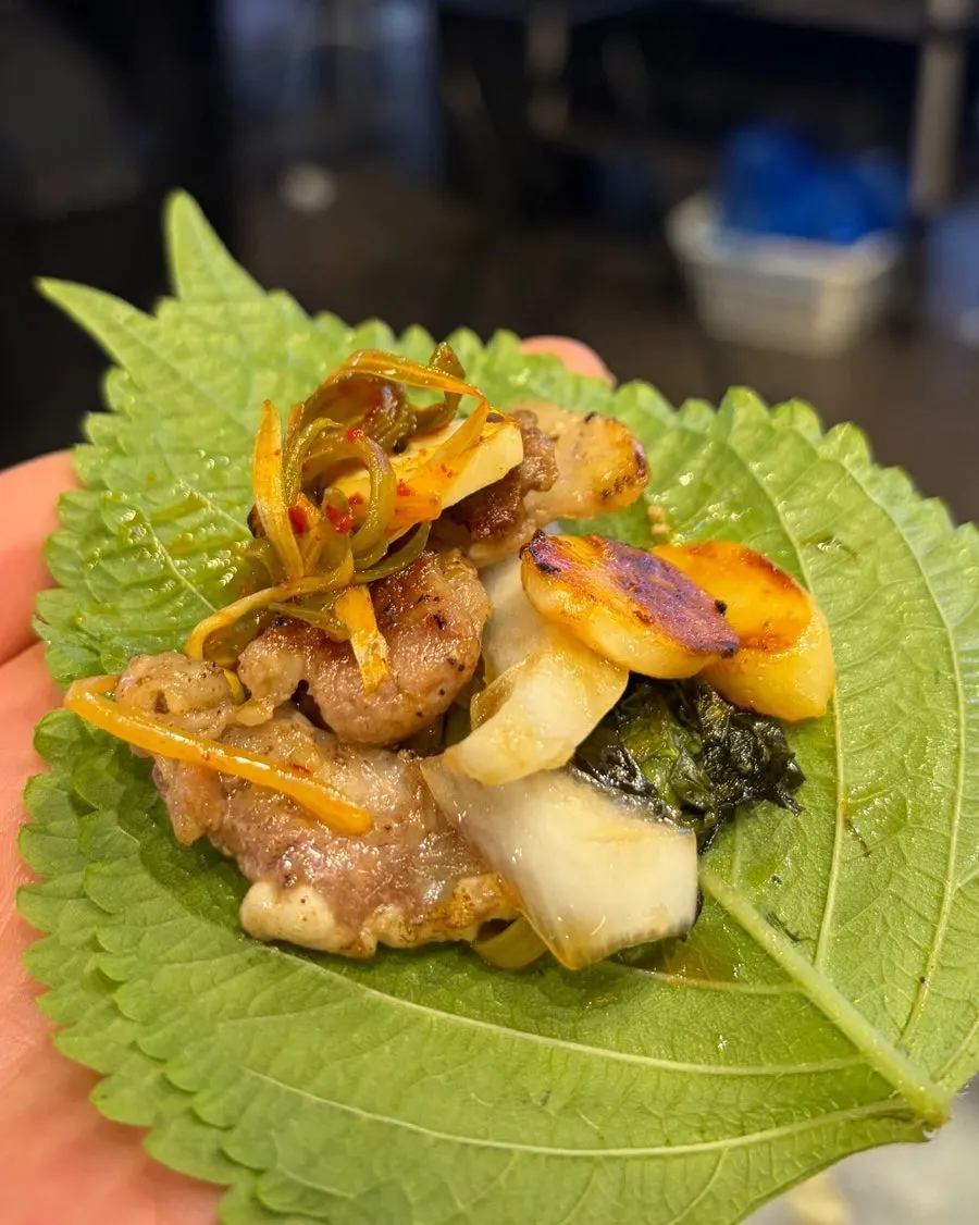 A lettuce wrap bite with shredded scallions