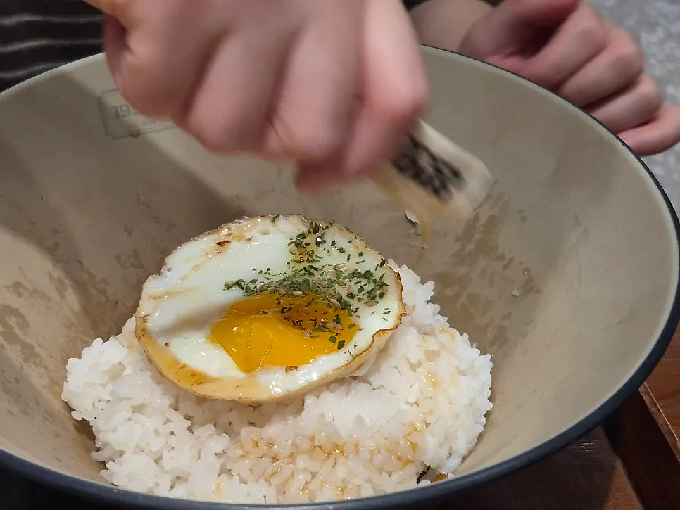 A bowl of rice topped with egg, seaweed, and sesame oil