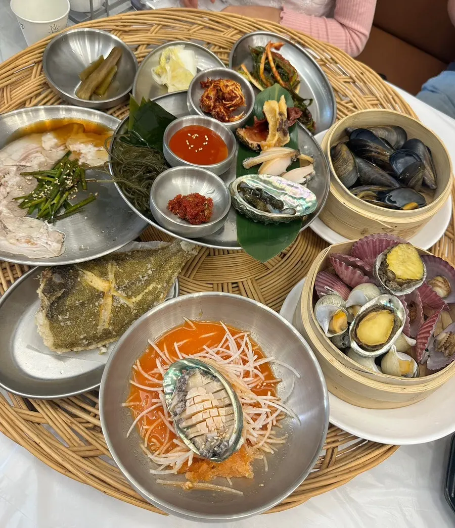 Haenyeo table with boiled pork belly, seafood, and cold raw fish soup