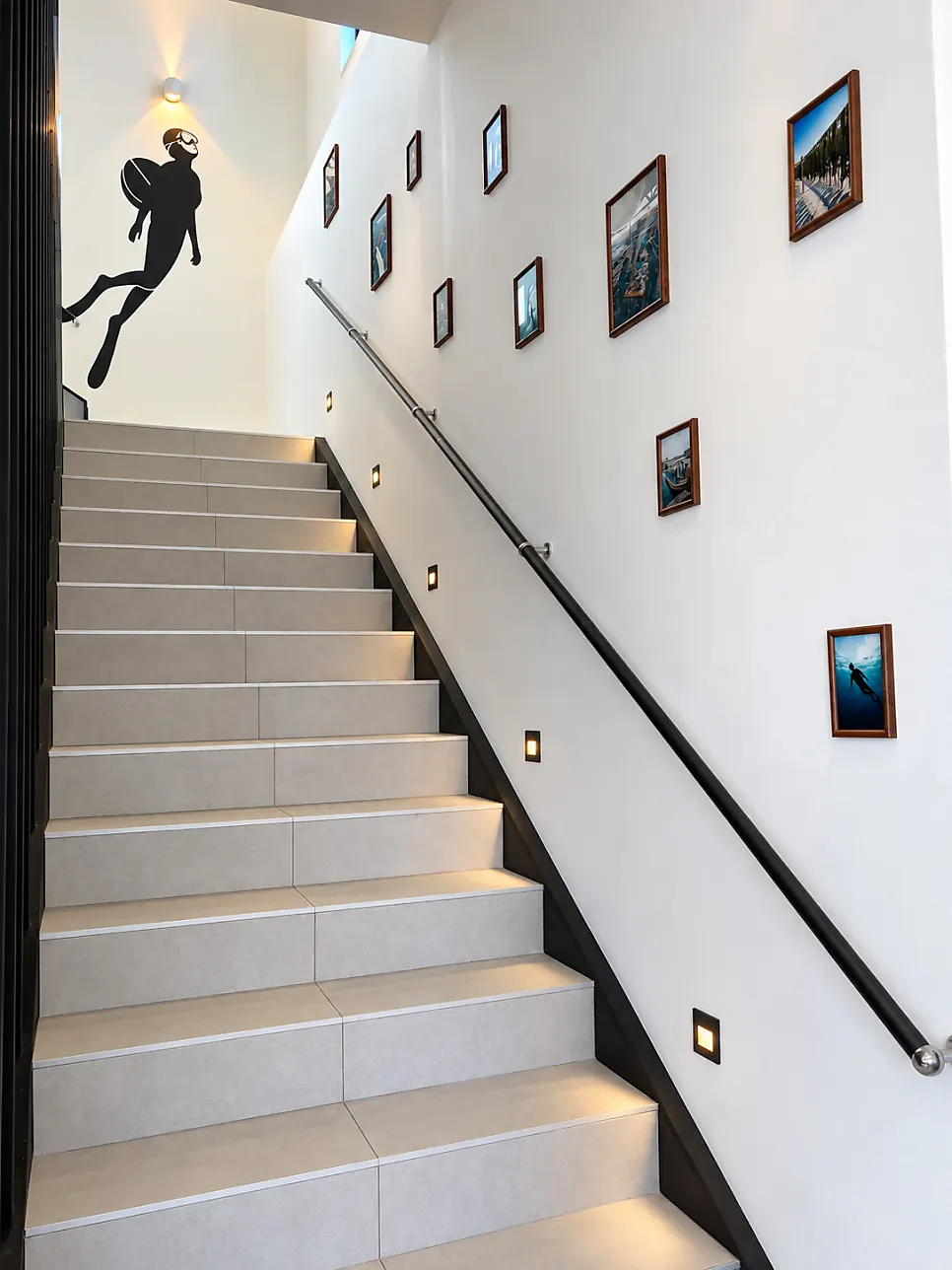 Framed pictures and haenyeo artwork beside the 2nd-floor stairs