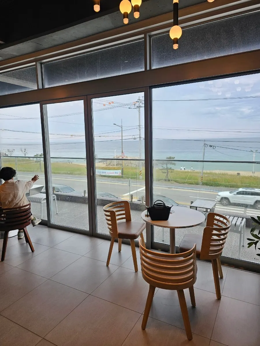 2nd-floor floor-to-ceiling window seats with ocean view at Baegya Coffee
