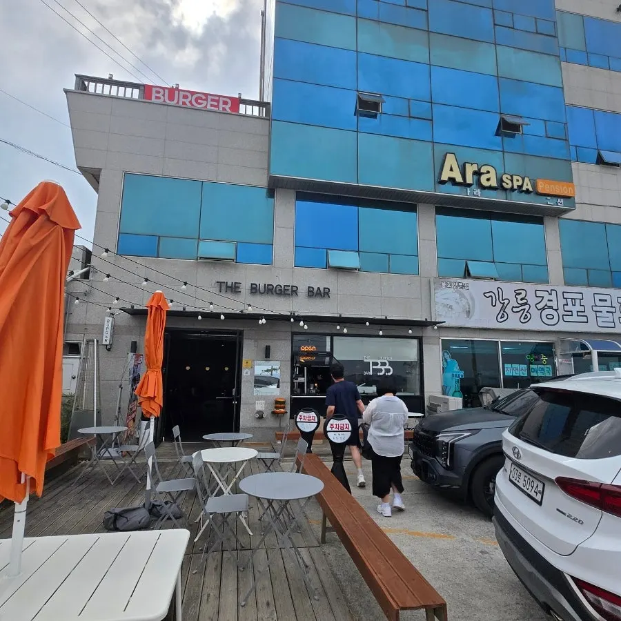 Burger Bar's outdoor tables and long bench with a view of the sea across the road