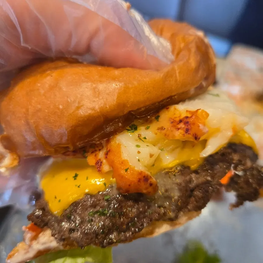 Layers of cheese, lobster meat, and vegetables inside the burger