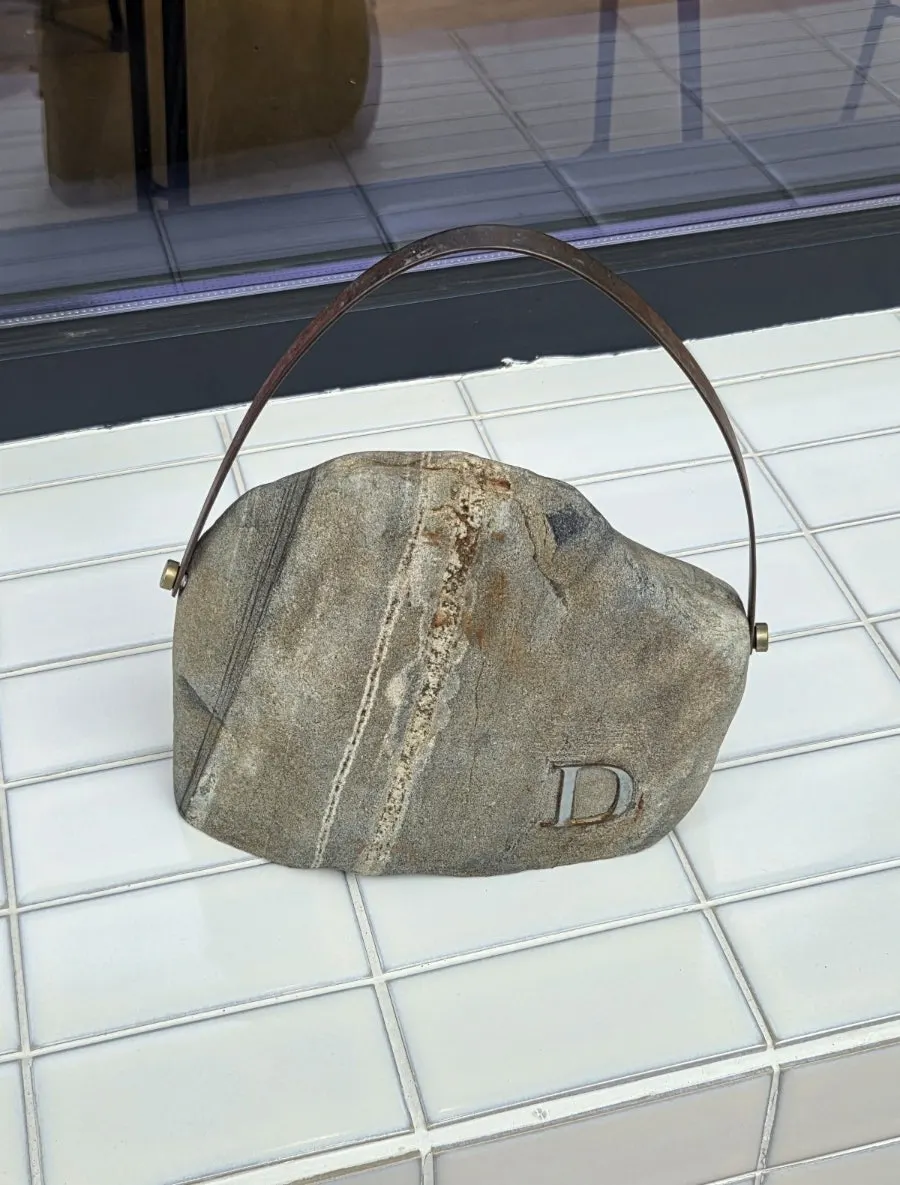A stone-shaped bag object styled like a luxury handbag