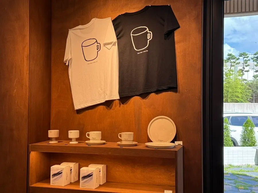 Coffee Dripper branded T-shirts and coffee cups on display
