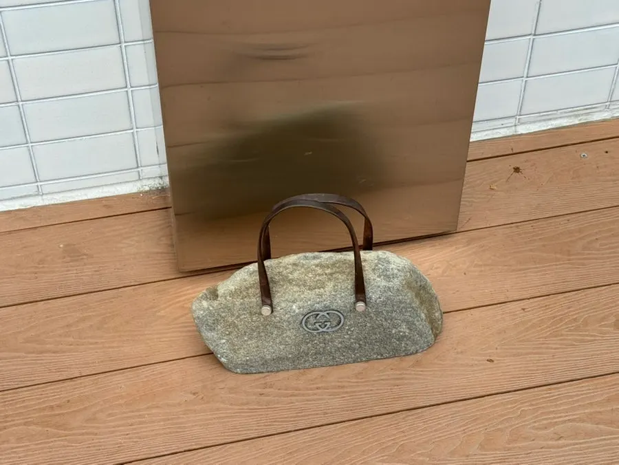 Stone object with luxury logo and bag handle