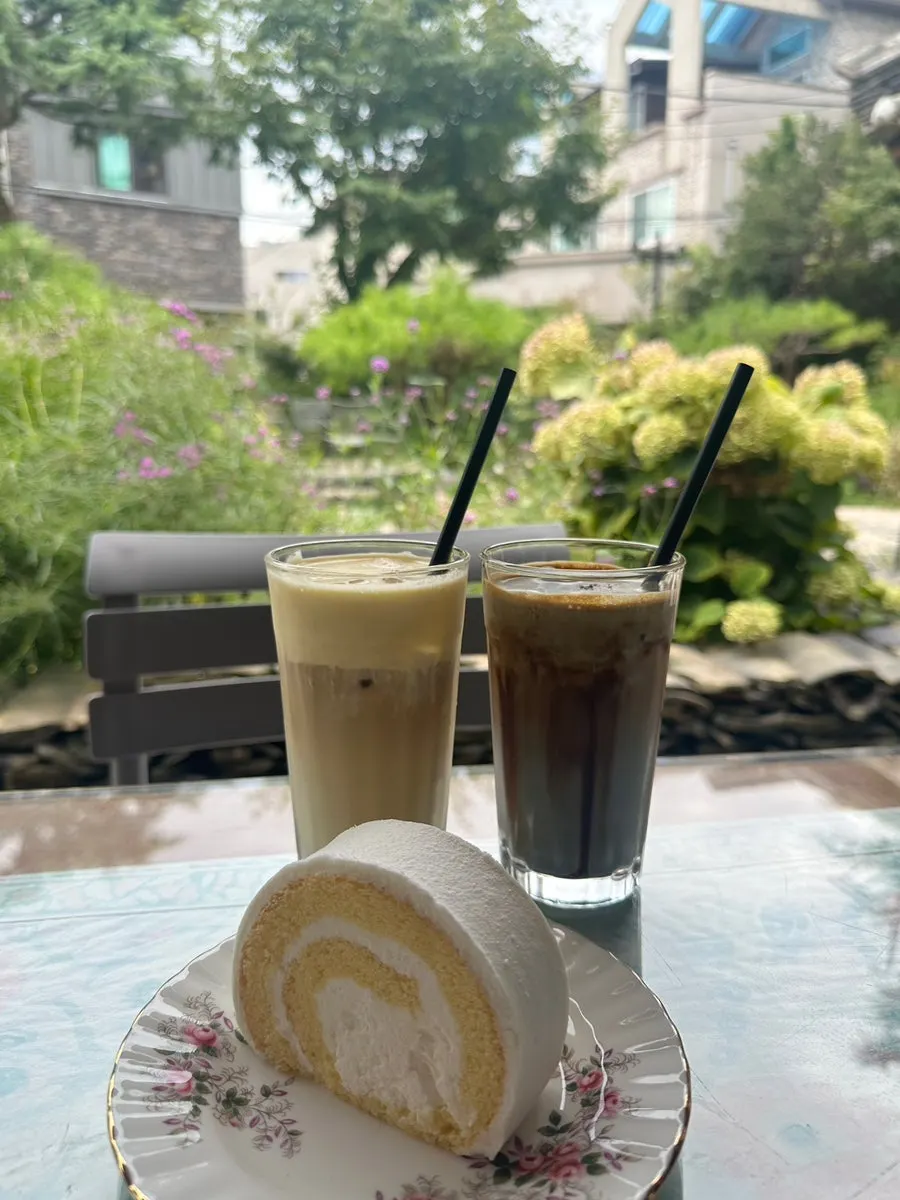 Drinks and roll cake set on an outdoor table at Cafe Giwa