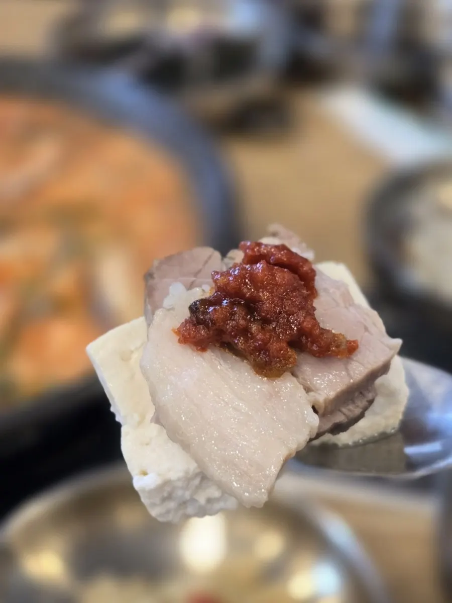 A bite of tofu topped with boiled pork and gajami-sikhae