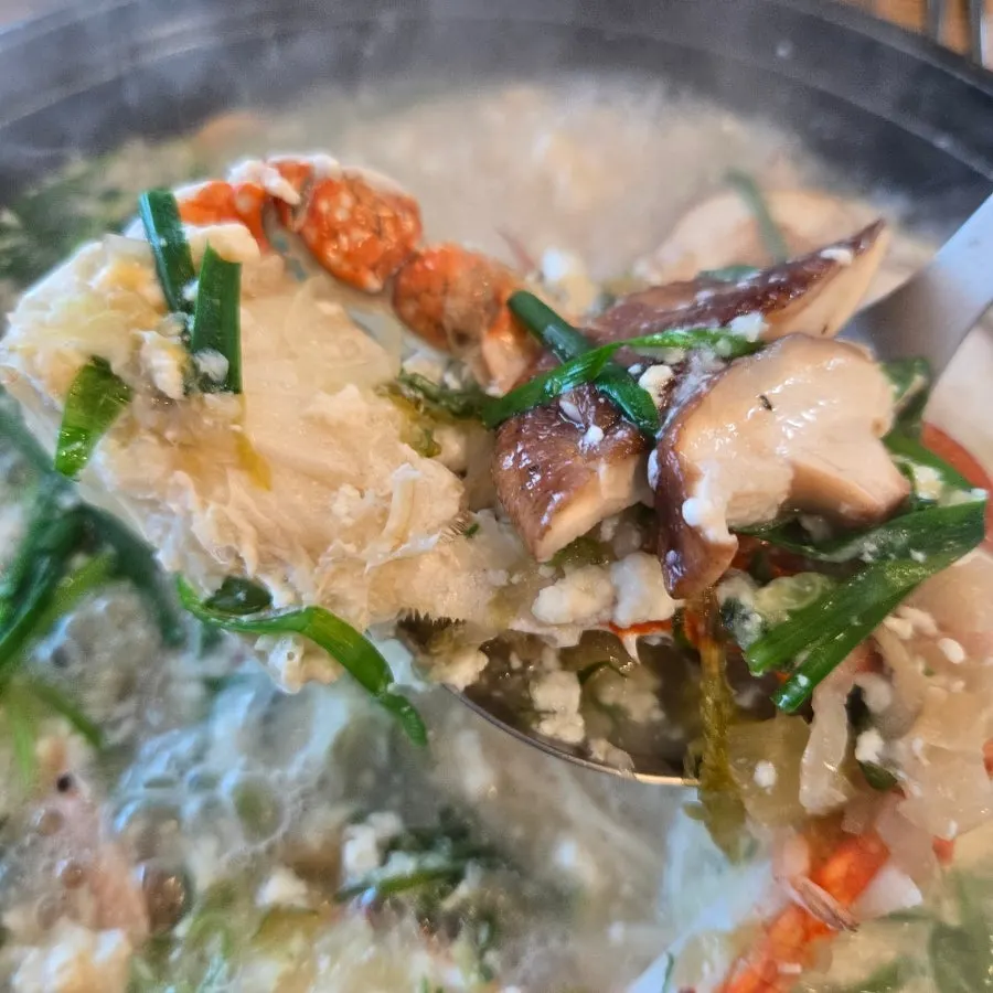 A spoonful of soft tofu lifted from the pot