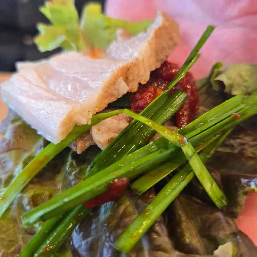 A bite of tofu topped with boiled pork and gajami-sikhae