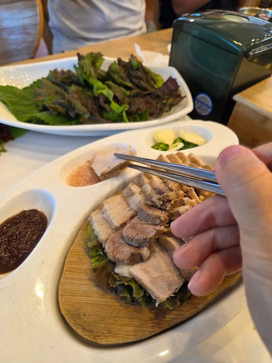 A bite of tofu topped with bossam and gajami sikhae