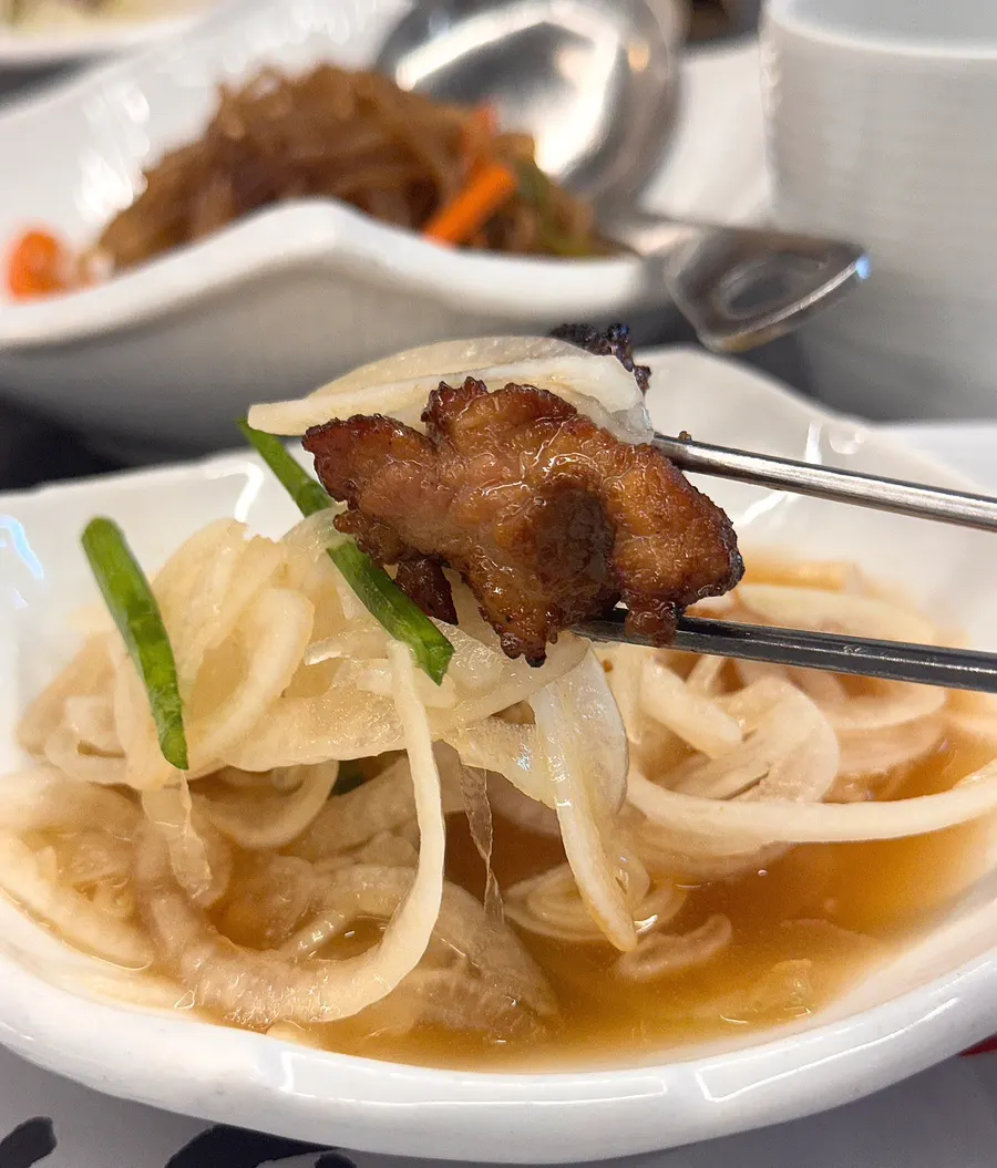 A piece of pork galbi picked up with chopsticks