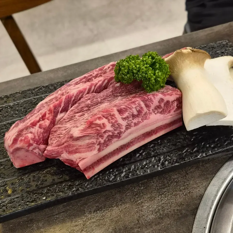 Woo-dae galbi plated with king oyster mushrooms and parsley