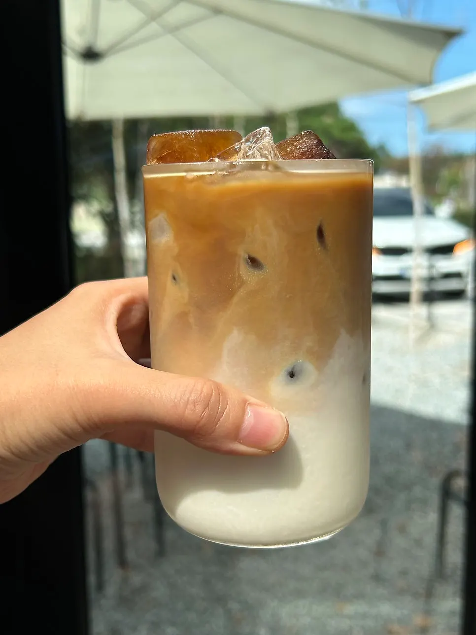 A glass of iced latte showing chunky coffee ice cubes
