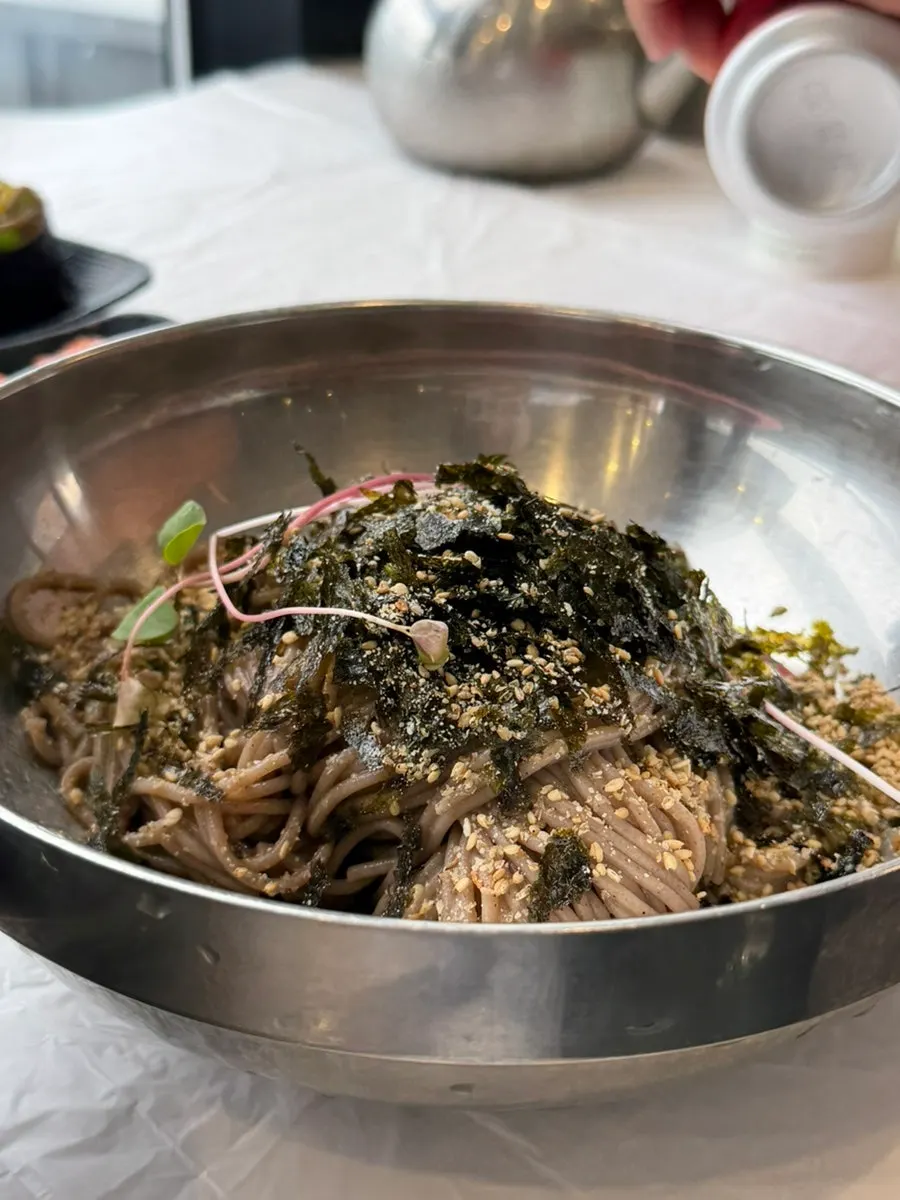 A bowl of perilla oil makguksu with a nutty aroma rising