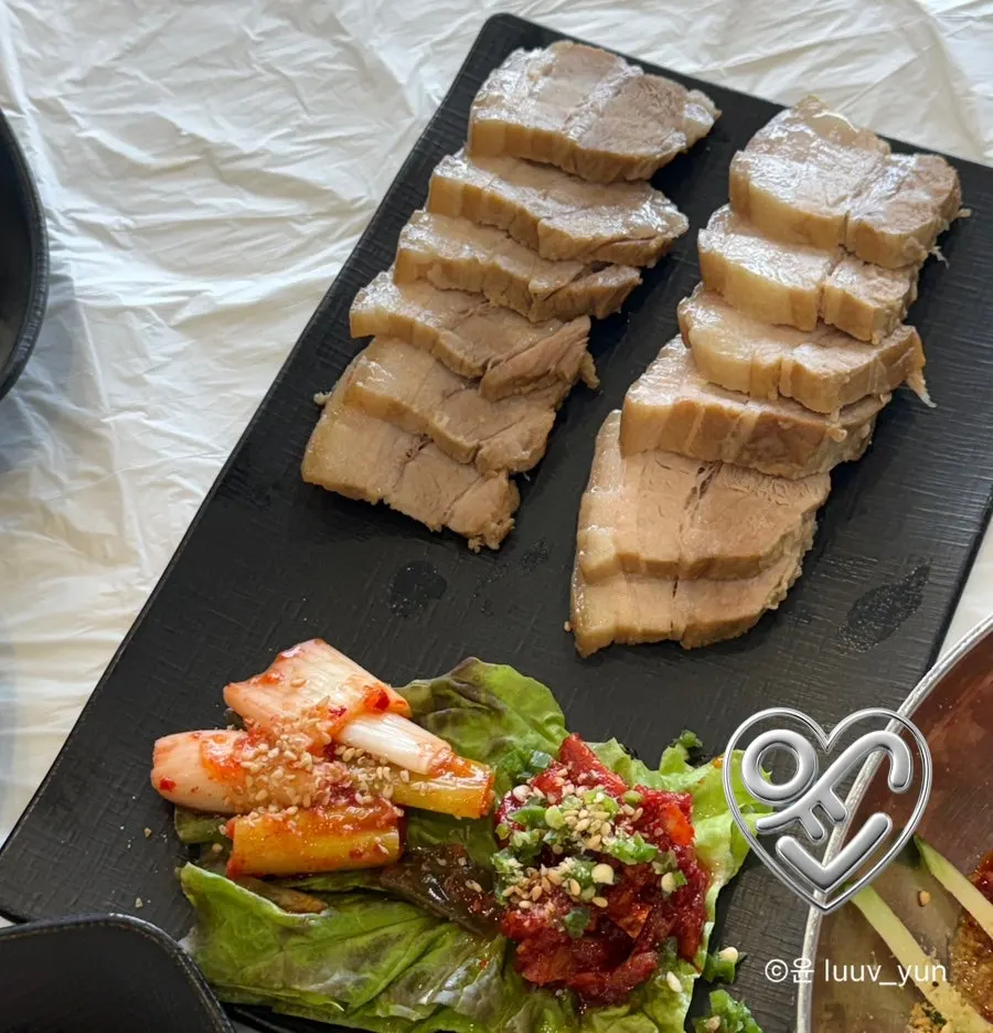 Table of makguksu and pork set by the ocean-view window