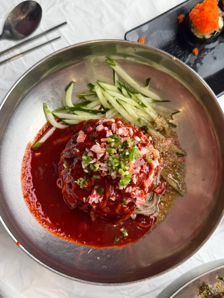 Spicy bibim makguksu topped with cucumber and garnish