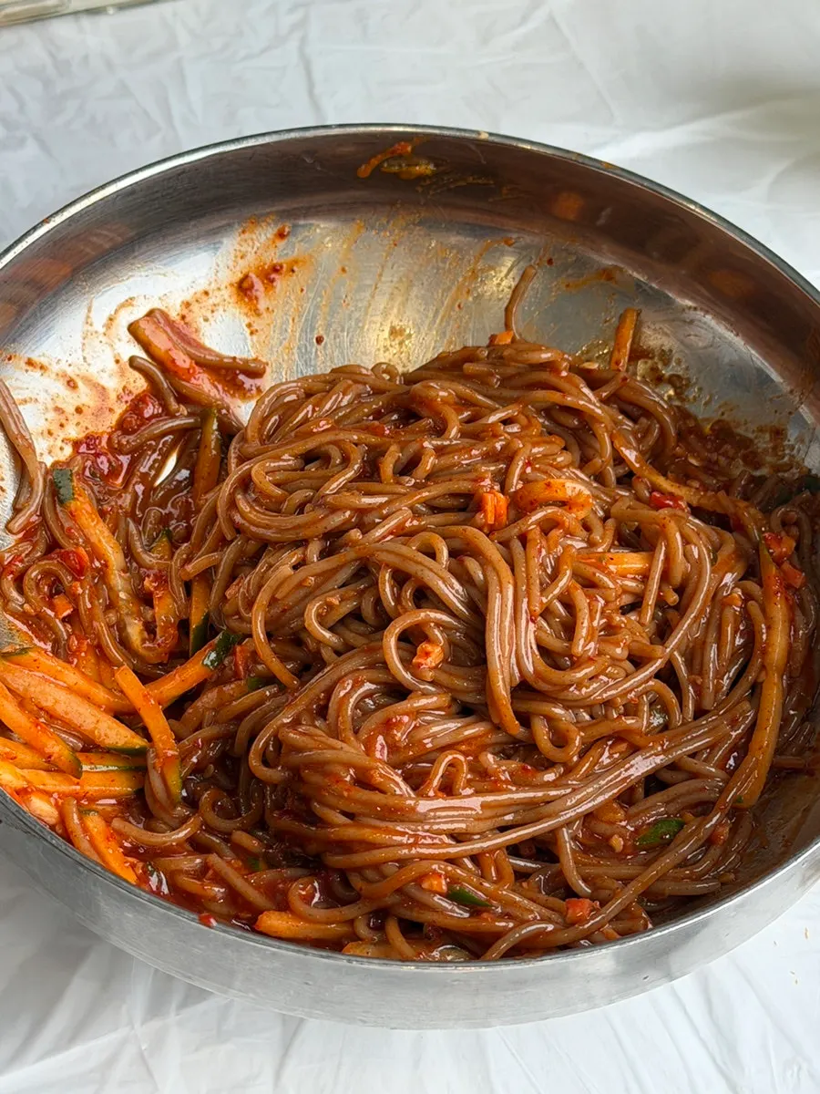 A chopstick-full of mixed spicy bibim makguksu