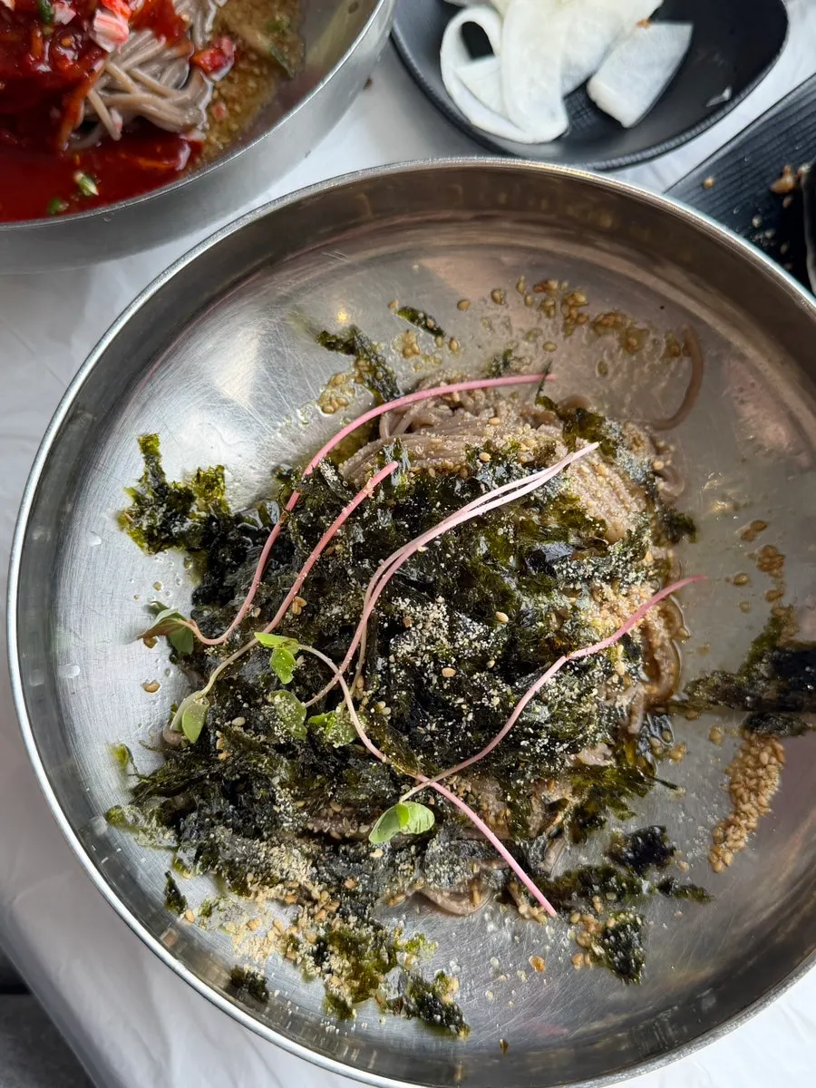 Perilla oil makguksu topped with seaweed flakes and sesame seeds
