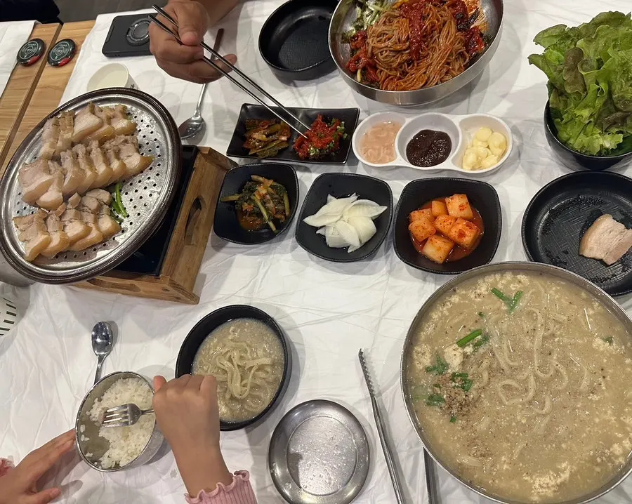 Full spread of pork, kalguksu, and makguksu on the table